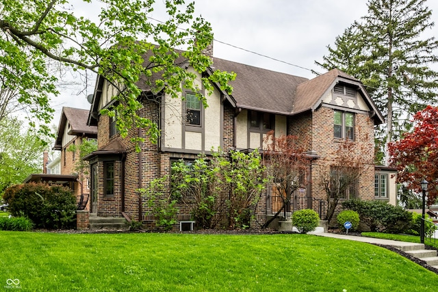 5124 N Capitol Ave, Indianapolis, IN 46208 - tudor home with a shingled roof, a front yard, and brick siding