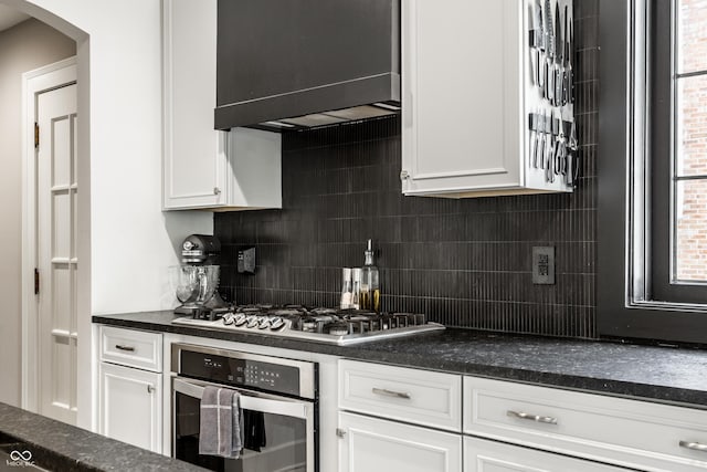 5124 N Capitol Ave, Indianapolis, IN 46208 - kitchen with backsplash, appliances with stainless steel finishes, arched walkways, white cabinets, and extractor fan