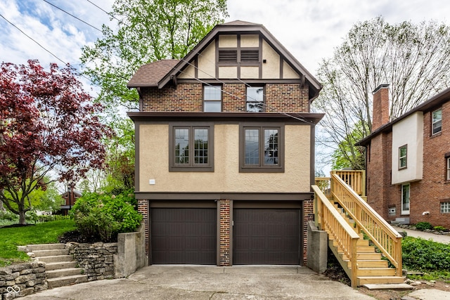 5124 N Capitol Ave, Indianapolis, IN 46208 - english style home with stucco siding, stairs, brick siding, an attached garage, and driveway