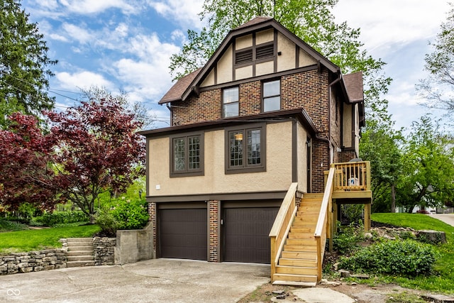 5124 N Capitol Ave, Indianapolis, IN 46208 - tudor-style house featuring a garage, brick siding, concrete driveway, stairs, and stucco siding