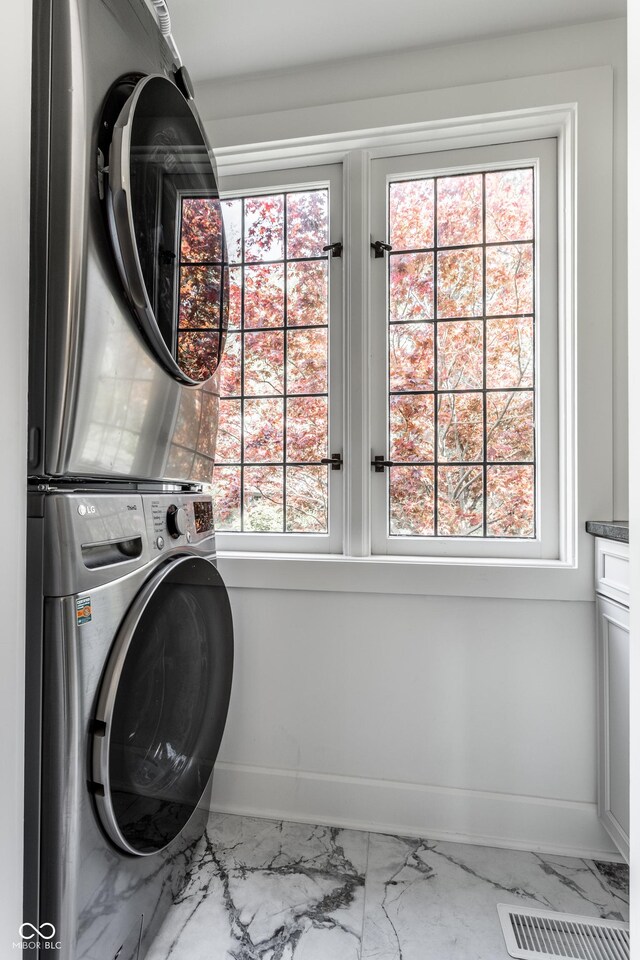 5124 N Capitol Ave, Indianapolis, IN 46208 - laundry room featuring baseboards, stacked washer and clothes dryer, marble finish floor, and cabinet space