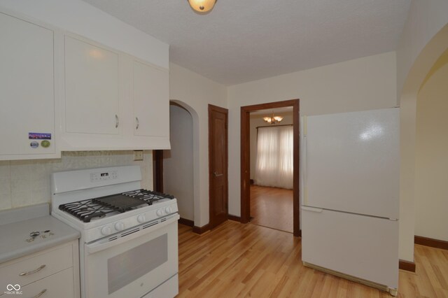 6051 Lowell Ave, Indianapolis, IN 46219 - kitchen with white appliances, arched walkways, decorative backsplash, light countertops, and light wood-style floors