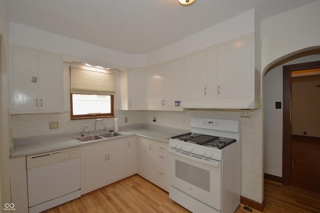6051 Lowell Ave, Indianapolis, IN 46219 - kitchen with white appliances, backsplash, arched walkways, light wood-style floors, and light countertops