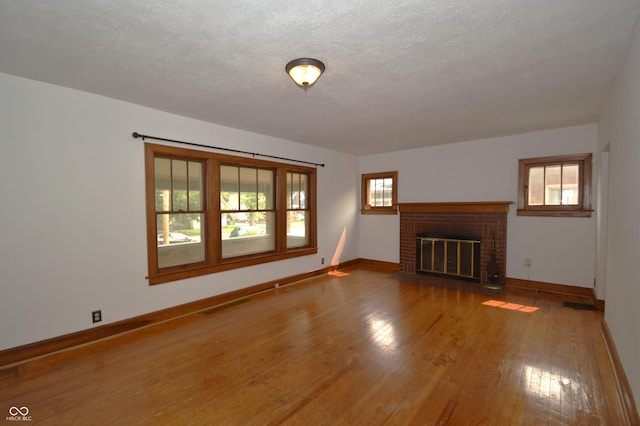 6051 Lowell Ave, Indianapolis, IN 46219 - unfurnished living room featuring wood finished floors, a brick fireplace, and a textured ceiling
