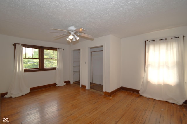 6051 Lowell Ave, Indianapolis, IN 46219 - unfurnished bedroom featuring multiple closets, light wood-type flooring, a textured ceiling, and a ceiling fan