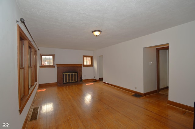 6051 Lowell Ave, Indianapolis, IN 46219 - unfurnished living room featuring a fireplace, light wood finished floors, and a textured ceiling