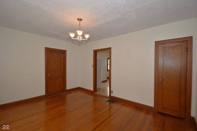 6051 Lowell Ave, Indianapolis, IN 46219 - empty room with wood finished floors, a chandelier, and a textured ceiling