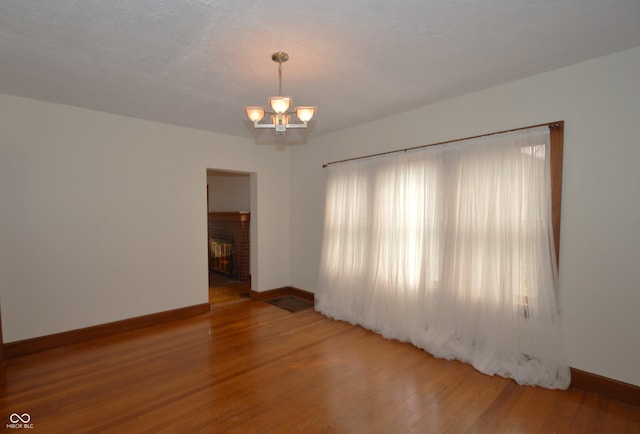 6051 Lowell Ave, Indianapolis, IN 46219 - empty room with a chandelier, wood finished floors, and a fireplace