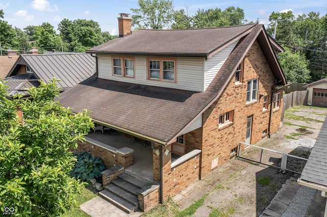 6051 Lowell Ave, Indianapolis, IN 46219 - rear view of house featuring a chimney, roof with shingles, brick siding, and a gate