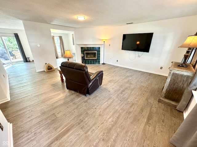 4223 Kestrel Ct, Indianapolis, IN 46254 - living area featuring baseboards, a textured ceiling, wood finished floors, and a tiled fireplace