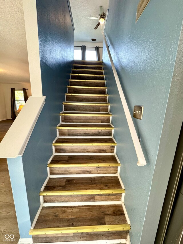 4223 Kestrel Ct, Indianapolis, IN 46254 - stairs featuring a textured ceiling, ceiling fan, a textured wall, and wood finished floors
