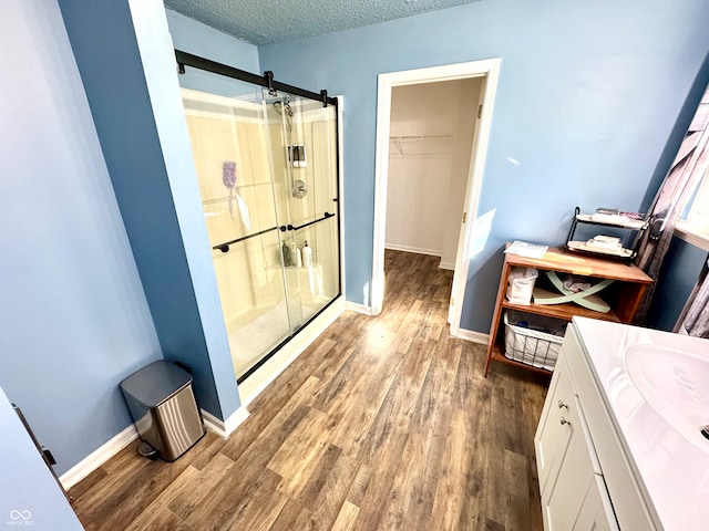 4223 Kestrel Ct, Indianapolis, IN 46254 - bathroom with a textured ceiling, baseboards, wood finished floors, and a stall shower