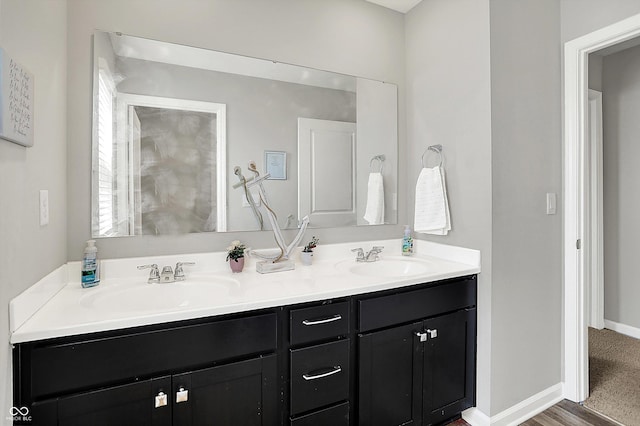 bathroom featuring double vanity, baseboards, and a sink