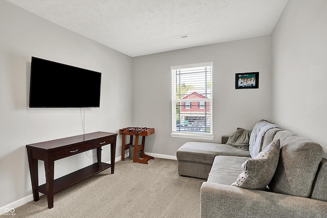 living area with baseboards, a textured ceiling, visible vents, and light carpet