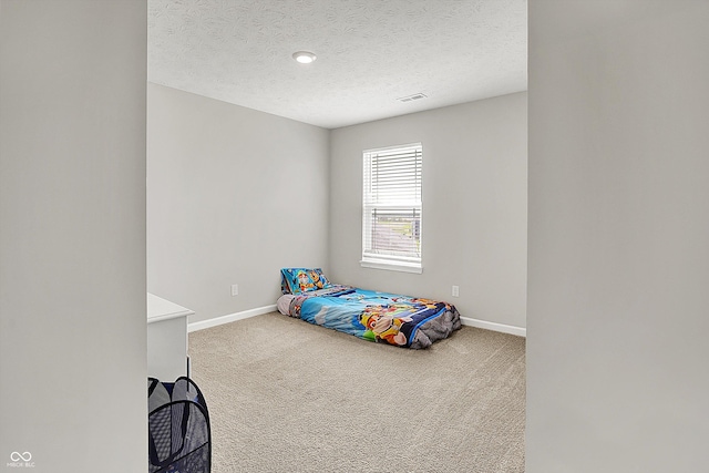 unfurnished bedroom with baseboards, a textured ceiling, carpet, and visible vents