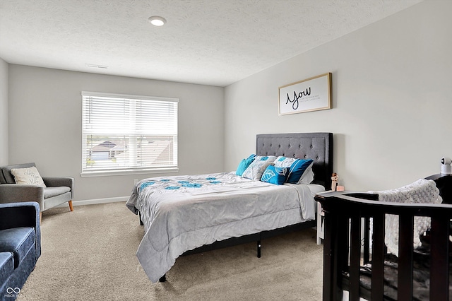 carpeted bedroom featuring baseboards, a textured ceiling, and visible vents