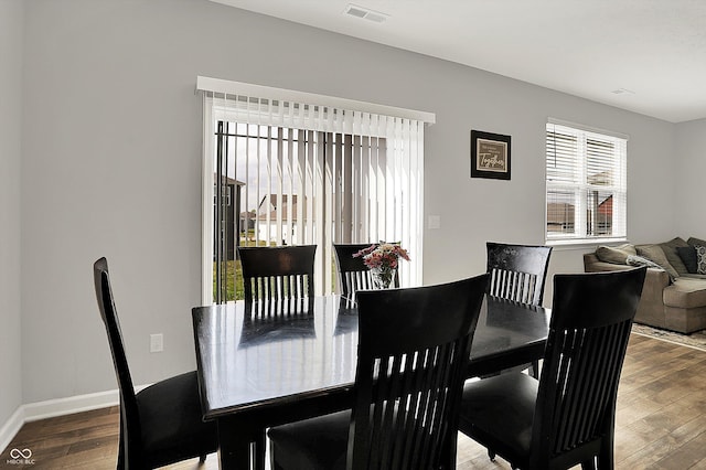 dining space featuring baseboards, wood finished floors, and visible vents