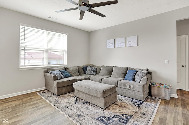living area featuring visible vents, baseboards, ceiling fan, and wood finished floors