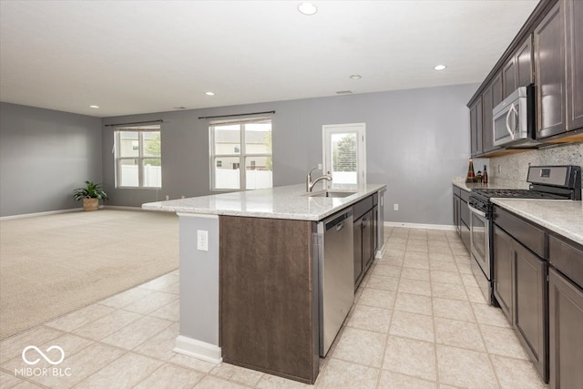 2006 Creek Bank Dr, Columbus, IN 47201 - kitchen with appliances with stainless steel finishes, a sink, a center island with sink, dark brown cabinetry, and baseboards