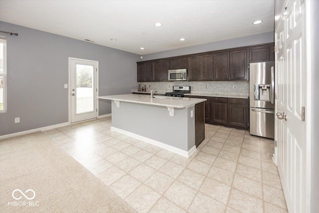2006 Creek Bank Dr, Columbus, IN 47201 - kitchen with stainless steel appliances, dark brown cabinets, an island with sink, a kitchen breakfast bar, and a sink