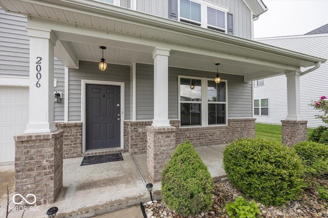 2006 Creek Bank Dr, Columbus, IN 47201 - doorway to property featuring covered porch, board and batten siding, brick siding, and a garage