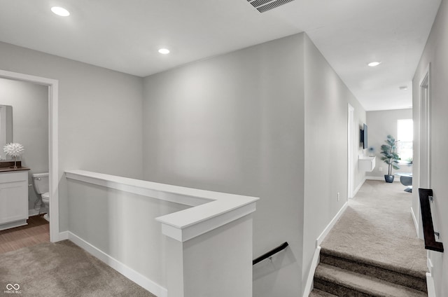 hall featuring carpet floors, baseboards, recessed lighting, and an upstairs landing