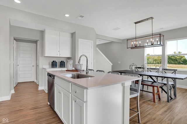 kitchen featuring dishwasher, a sink, baseboards, light countertops, and a breakfast bar