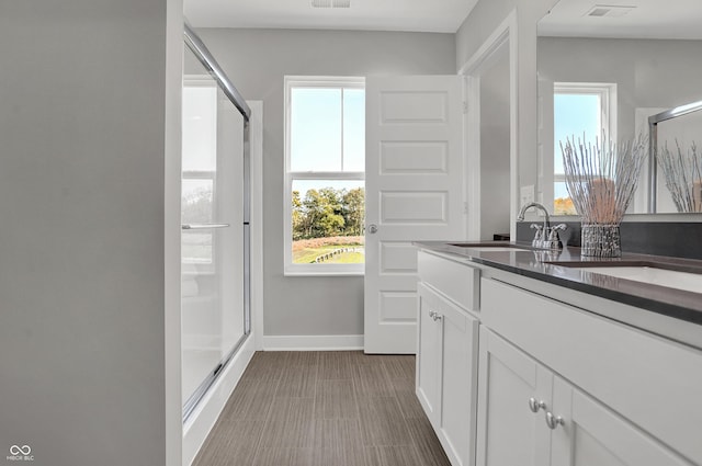 full bathroom featuring vanity, baseboards, visible vents, and a stall shower