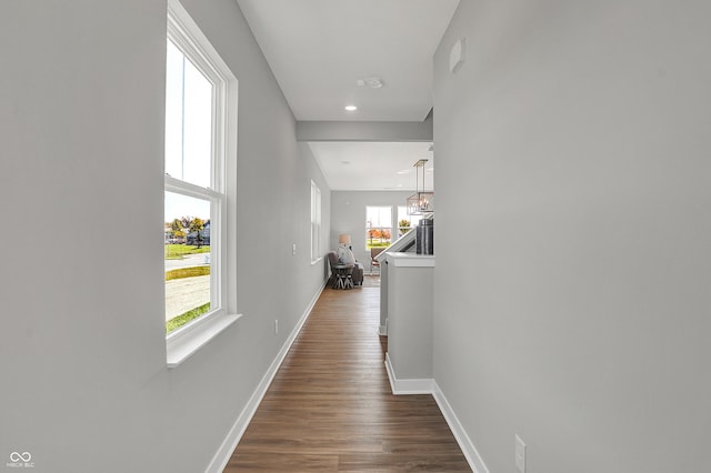 corridor featuring baseboards, recessed lighting, dark wood finished floors, and a wealth of natural light