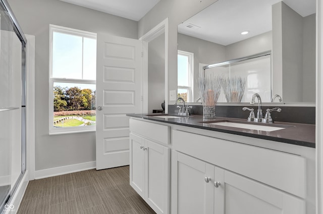 bathroom with baseboards, a wealth of natural light, a sink, and a stall shower