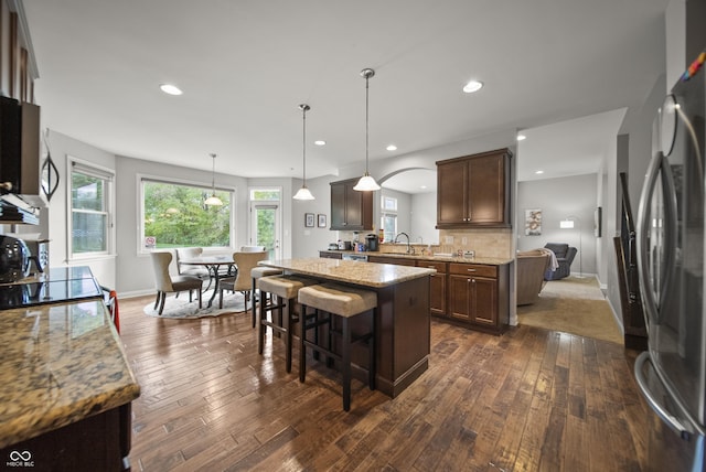 kitchen featuring freestanding refrigerator, a sink, dark wood finished floors, and light stone countertops