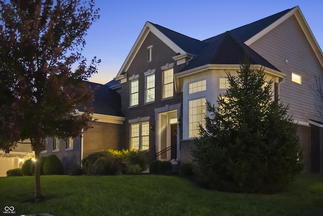 traditional home featuring brick siding and a yard