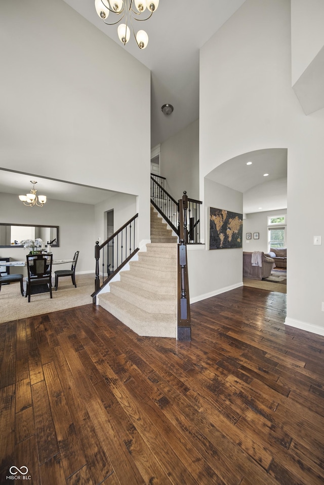 interior space with an inviting chandelier, wood-type flooring, a high ceiling, and stairway