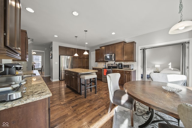 kitchen with a kitchen island, dark brown cabinetry, appliances with stainless steel finishes, and dark wood finished floors