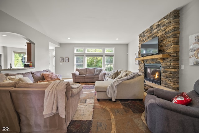 living area featuring arched walkways, a fireplace, recessed lighting, and wood finished floors