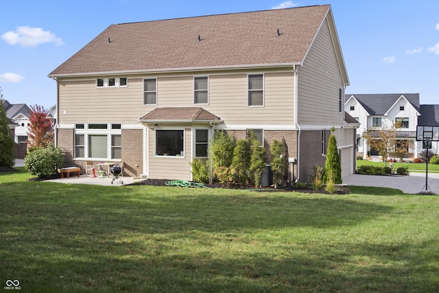 back of property featuring brick siding, a garage, a yard, and a patio