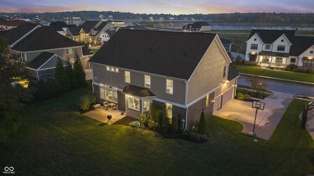 aerial view at dusk featuring a residential view and a water view