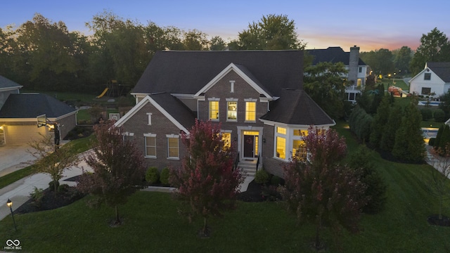 traditional-style house with a lawn, brick siding, and concrete driveway