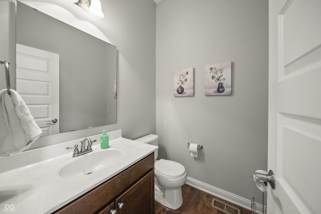 bathroom featuring vanity, toilet, baseboards, wood finished floors, and visible vents