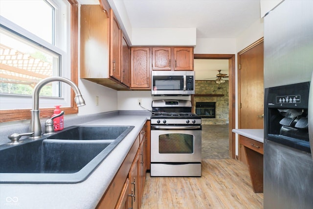 403 Hawthorn Dr, Crawfordsville, IN 47933 - kitchen featuring a sink, brown cabinetry, light wood-style flooring, stainless steel appliances, and a ceiling fan
