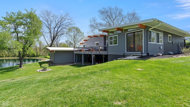 back of property with a lawn and a deck with water view