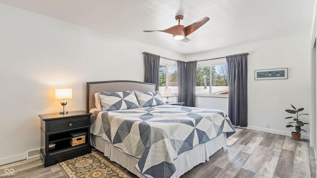 bedroom featuring baseboards, ceiling fan, wood finished floors, and visible vents