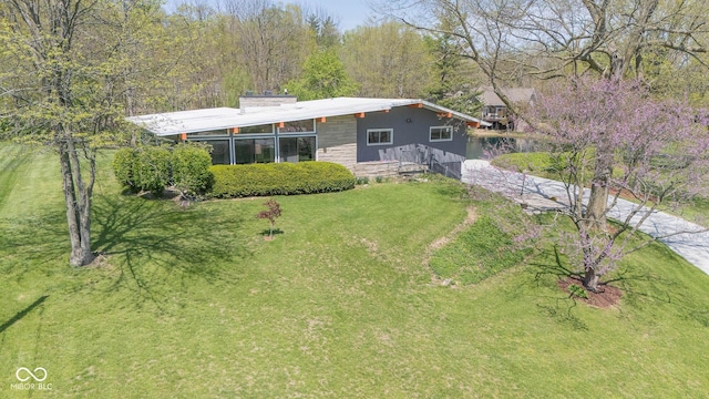 view of front facade featuring driveway, a front lawn, and stone siding