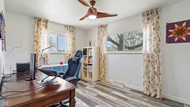 office space with visible vents, a ceiling fan, light wood-style floors, and baseboards