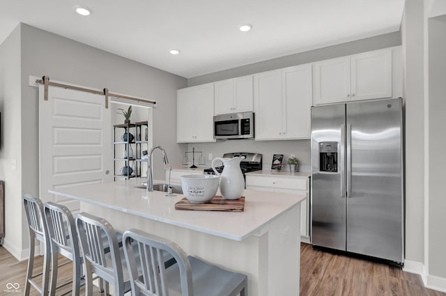 7645 Marin Pkwy, Cumberland, IN 46229 - kitchen with light wood-type flooring, a barn door, white cabinetry, a sink, and stainless steel appliances