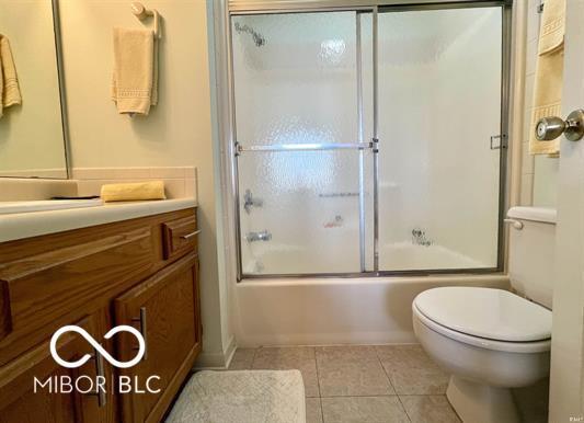 bathroom with vanity, combined bath / shower with glass door, tile patterned floors, and toilet