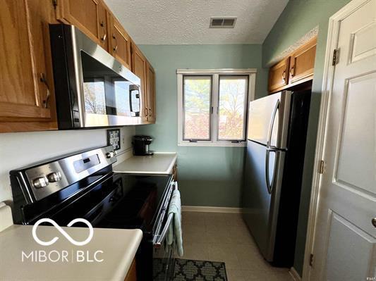 kitchen featuring brown cabinets, baseboards, appliances with stainless steel finishes, and visible vents