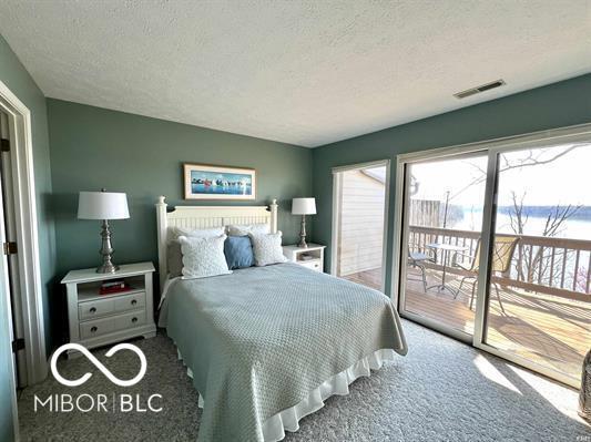 carpeted bedroom featuring access to outside, a textured ceiling, and visible vents