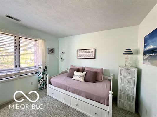 carpeted bedroom with a textured ceiling and visible vents