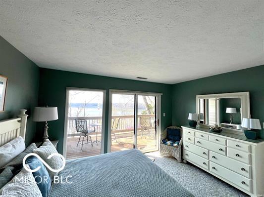 bedroom with access to outside, a textured ceiling, and light carpet